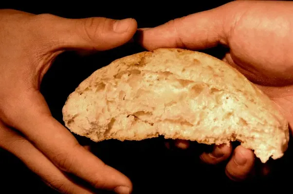 a hand giving another hand a piece of bread