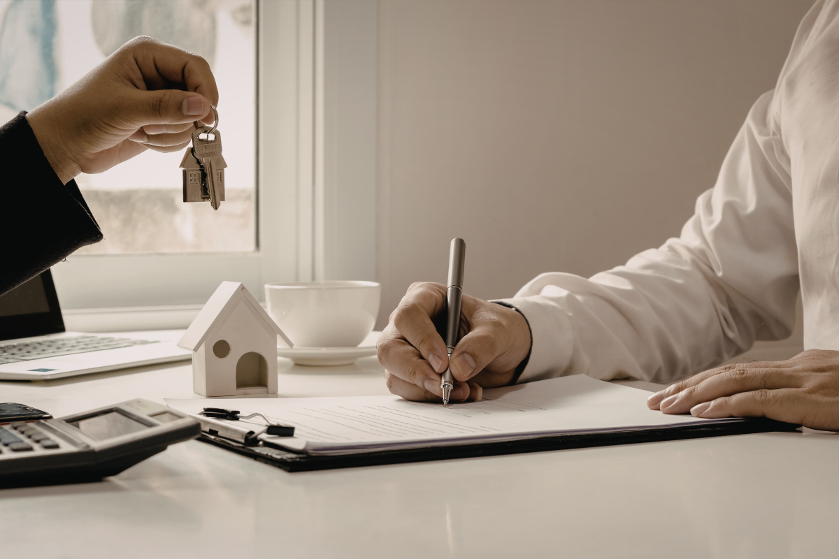 Hands exchanging documents at a counter, possibly a transaction or signing process.