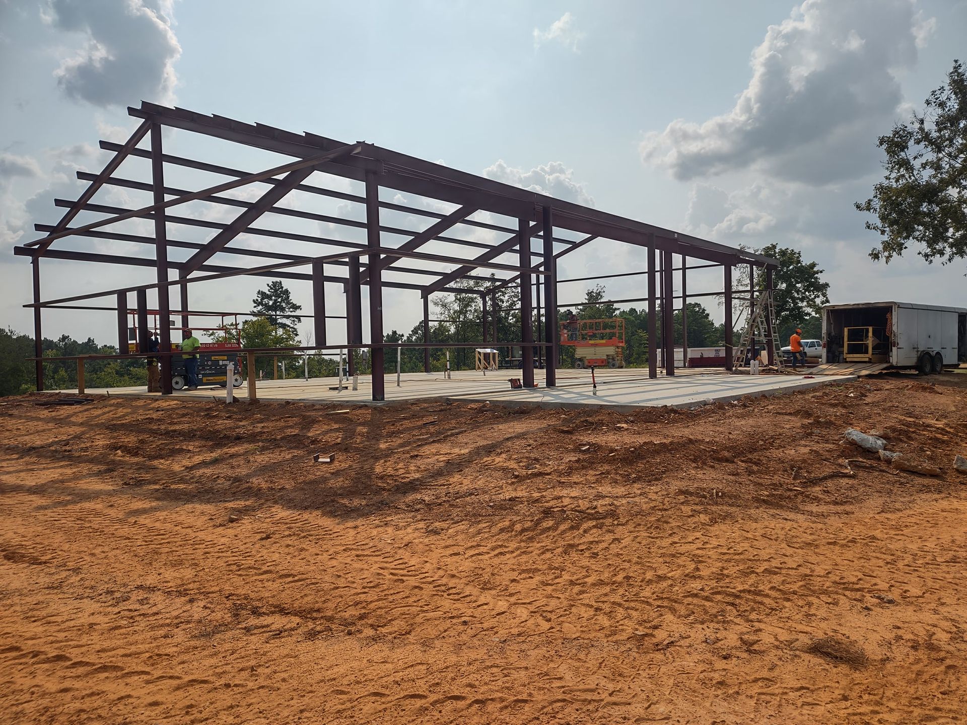 A large metal structure is being built in a dirt field.