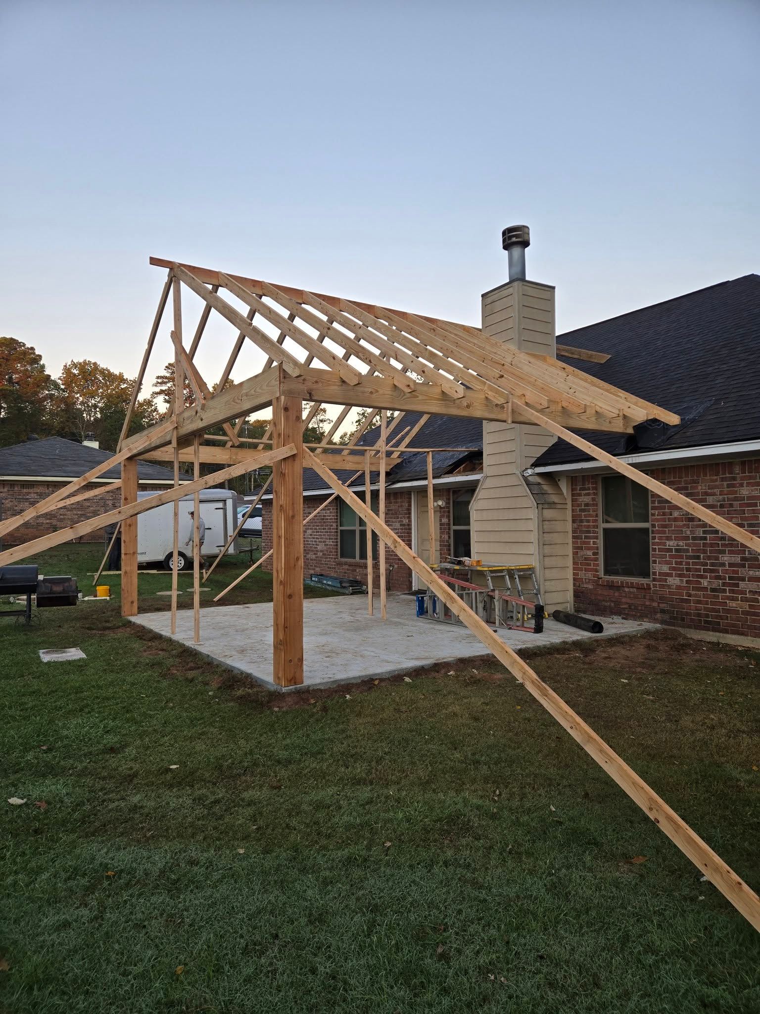 A wooden structure is being built in the backyard of a house.