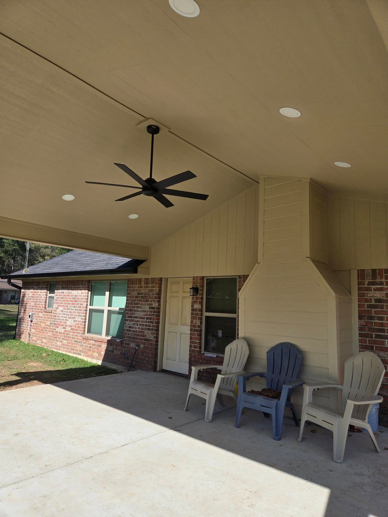 A patio with chairs , a table and a ceiling fan.