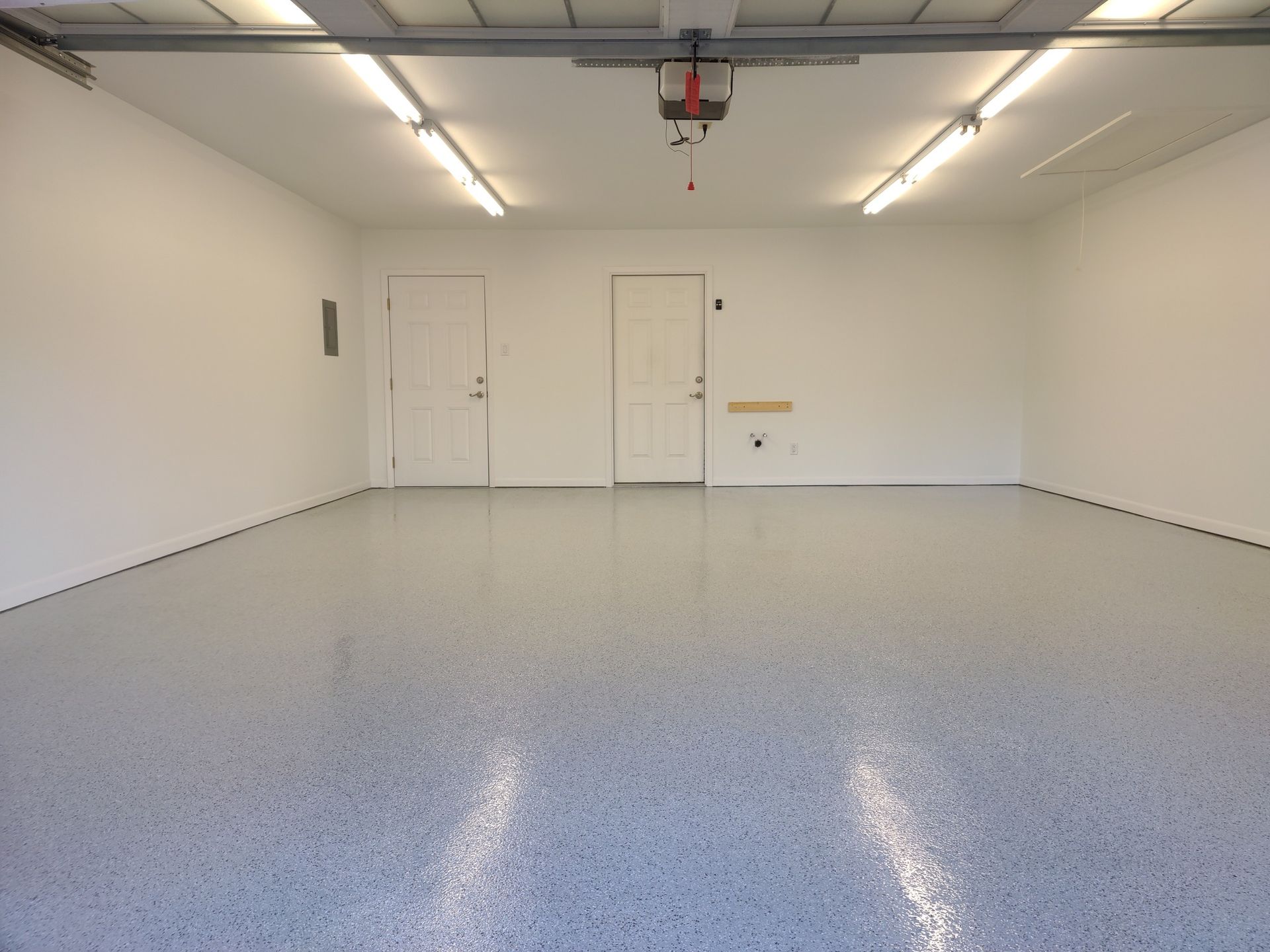 An empty garage with a gray floor and white walls