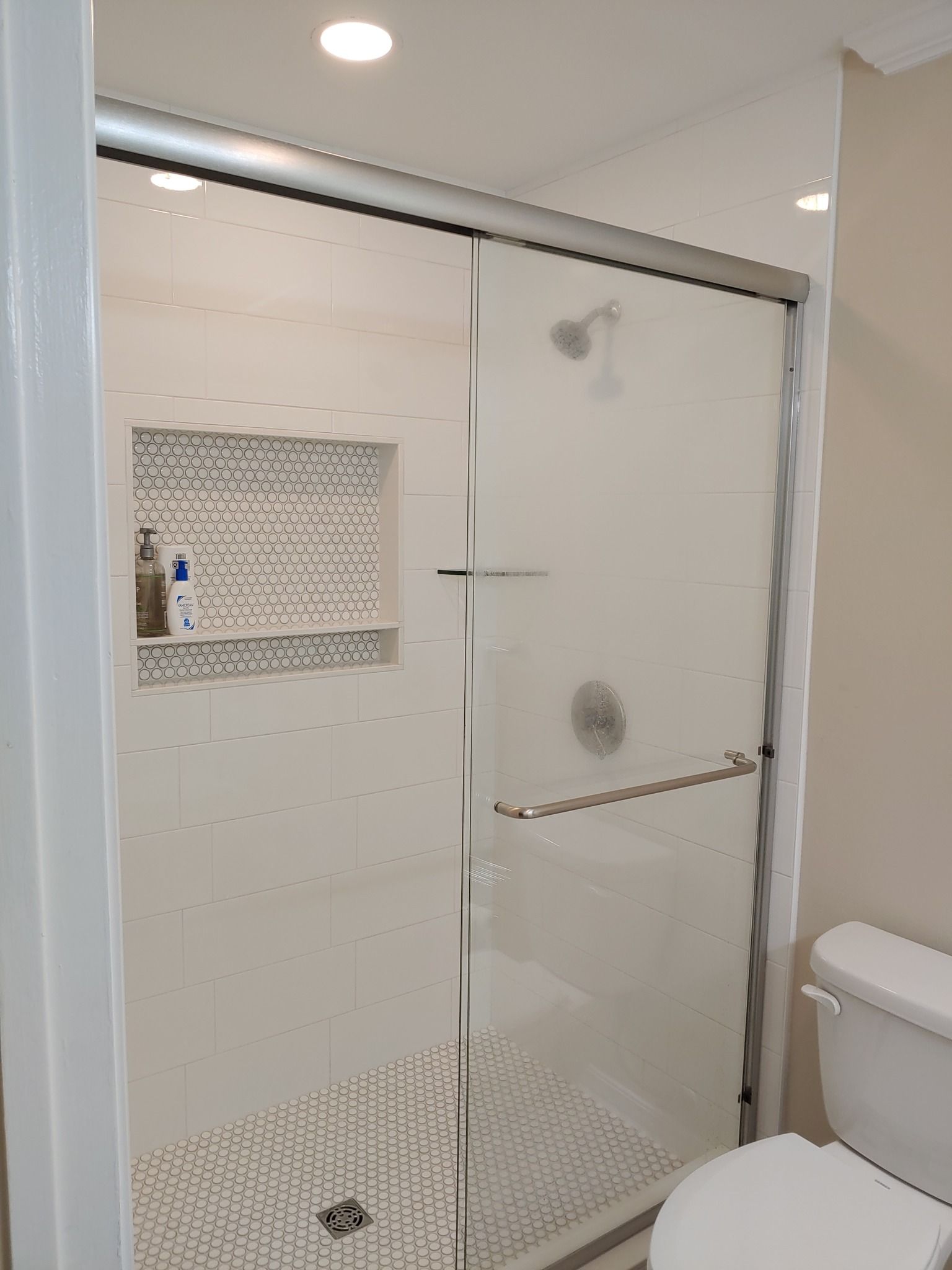 A bathroom with a toilet and a walk in shower with a glass door.