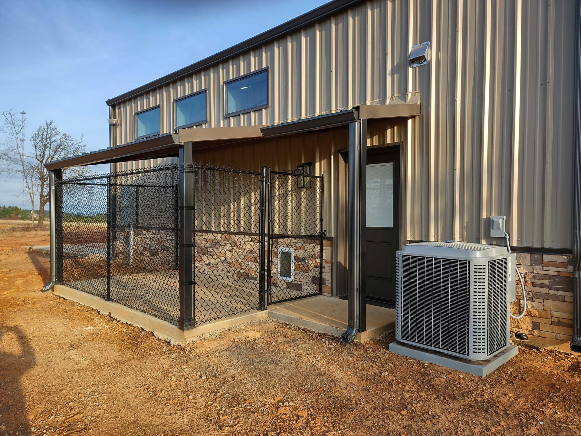 A building with a dog kennel and a air conditioner on the side of it.