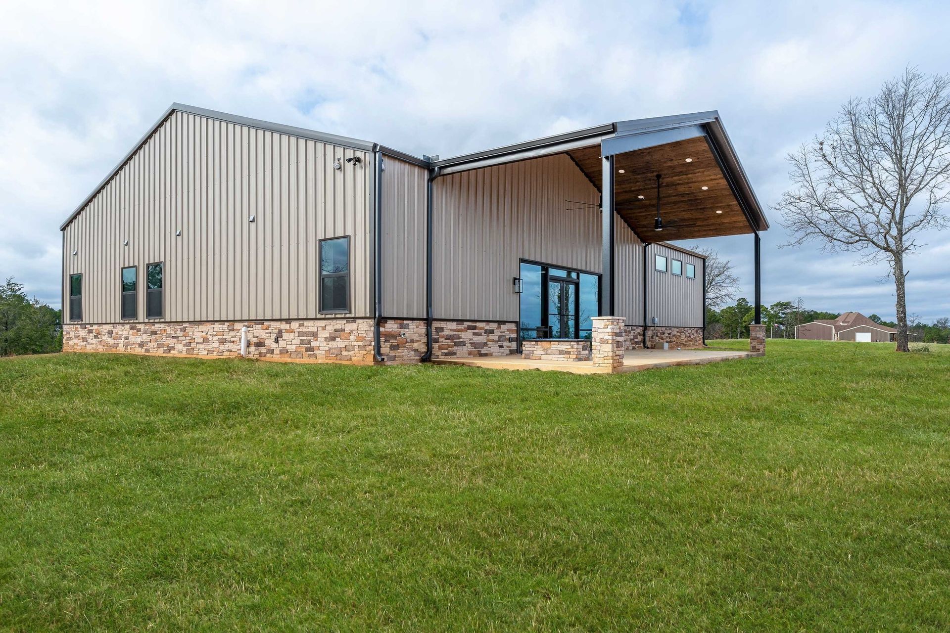 A large metal building is sitting on top of a lush green field.