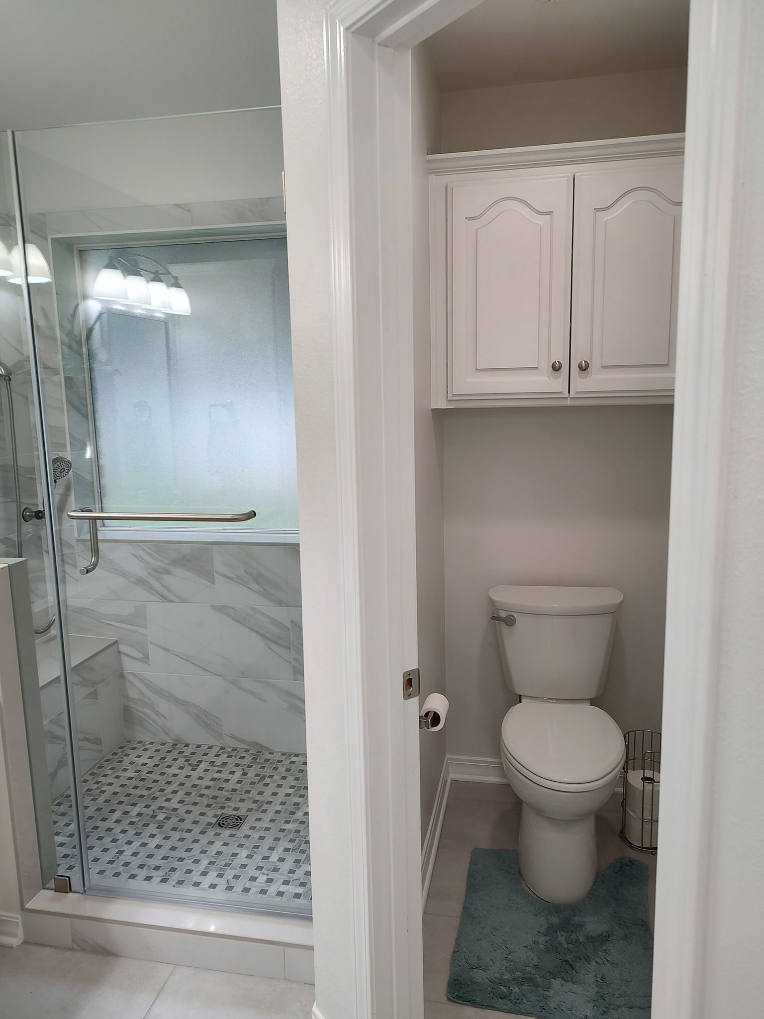 A bathroom with a toilet , shower , and cabinets.