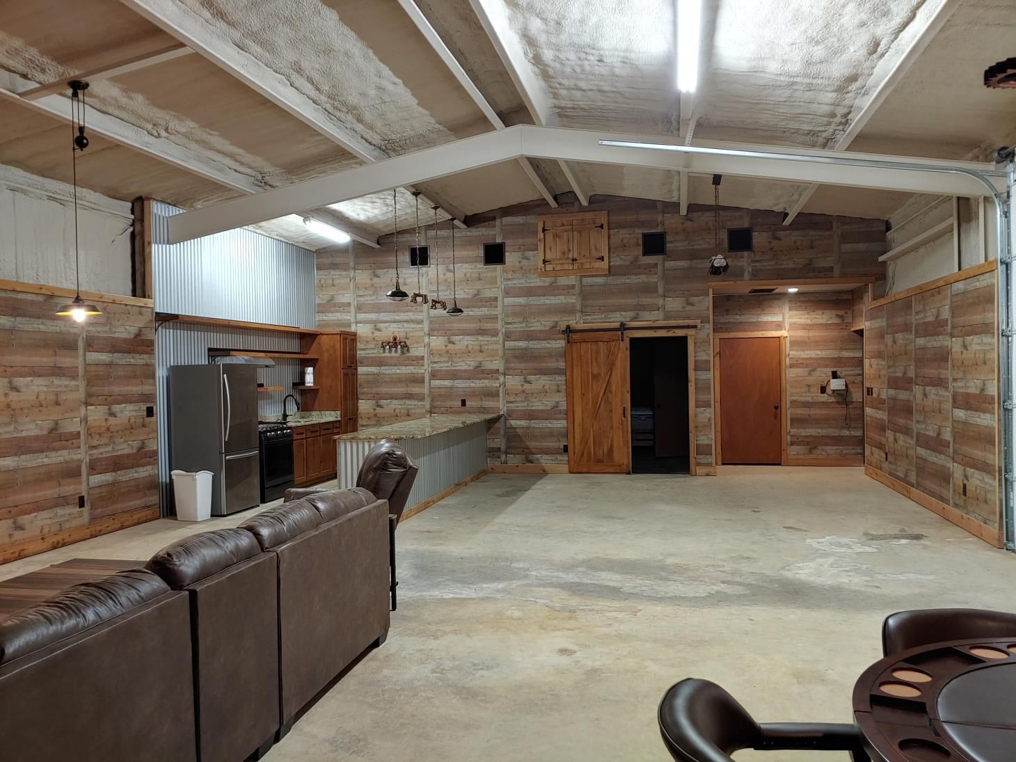 A living room with a couch , table , chairs and a refrigerator.