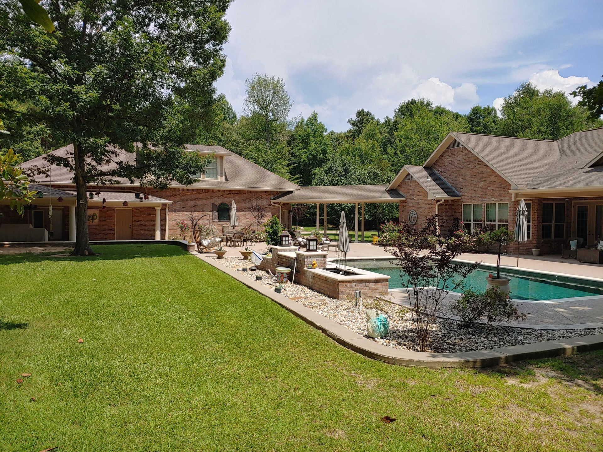 A large brick house with a large swimming pool in the backyard.
