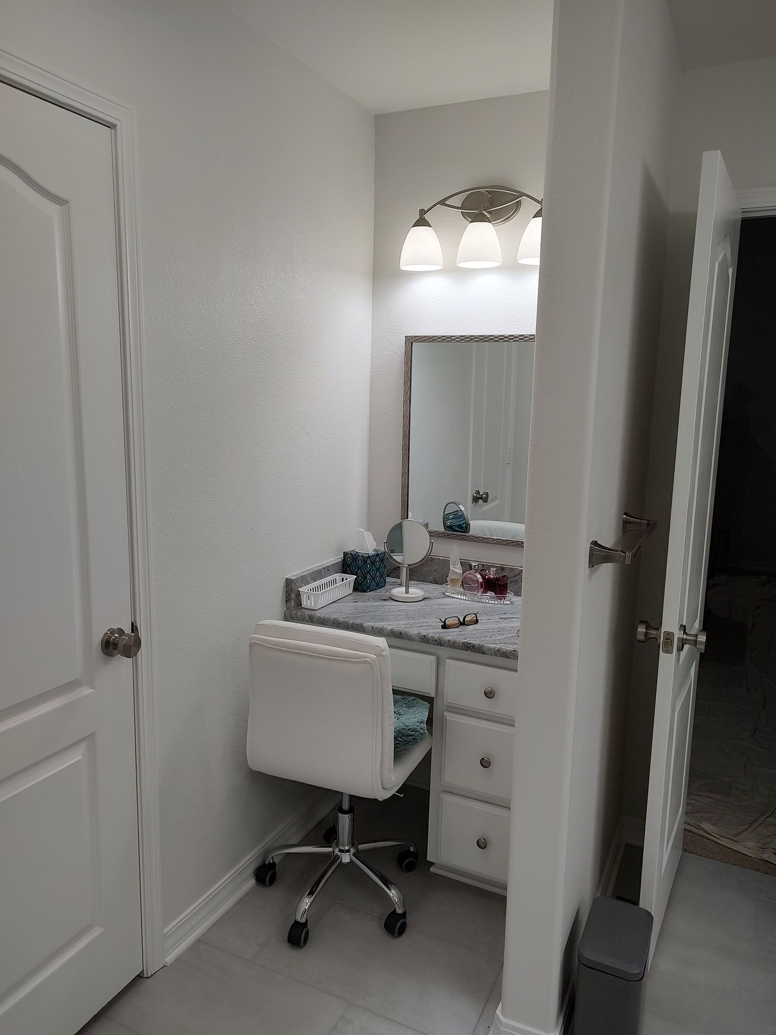 There is a vanity with a chair and a mirror in the bathroom.