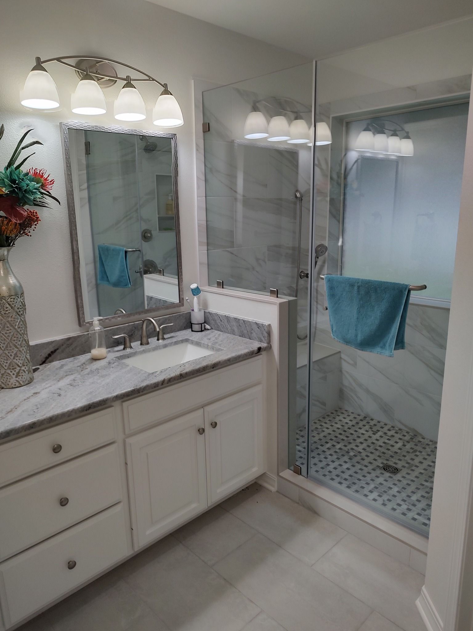 A bathroom with a sink , mirror and walk in shower.