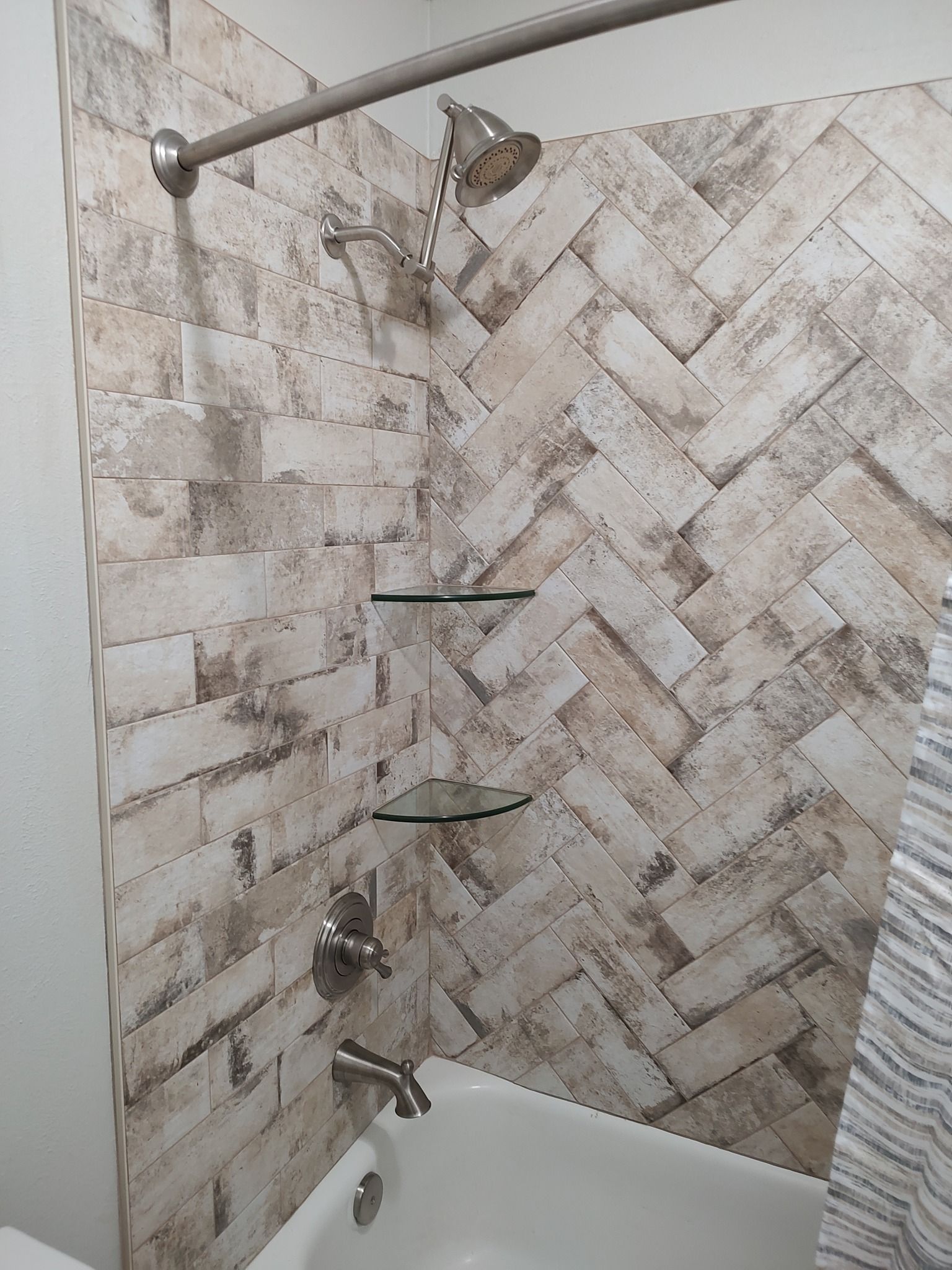 A bathroom with a bathtub , shower , and brick wall.