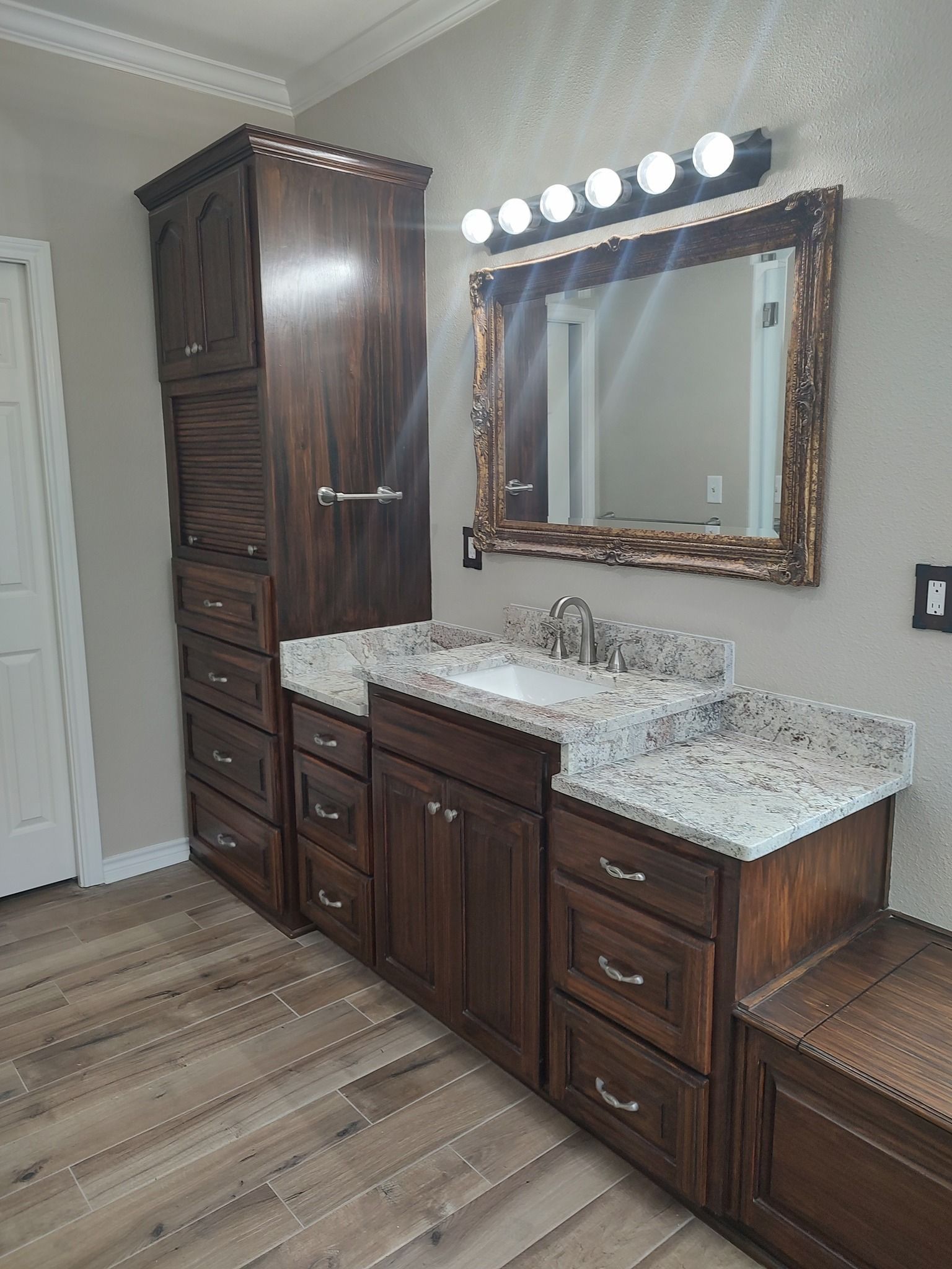 A bathroom with a sink , mirror and cabinets.
