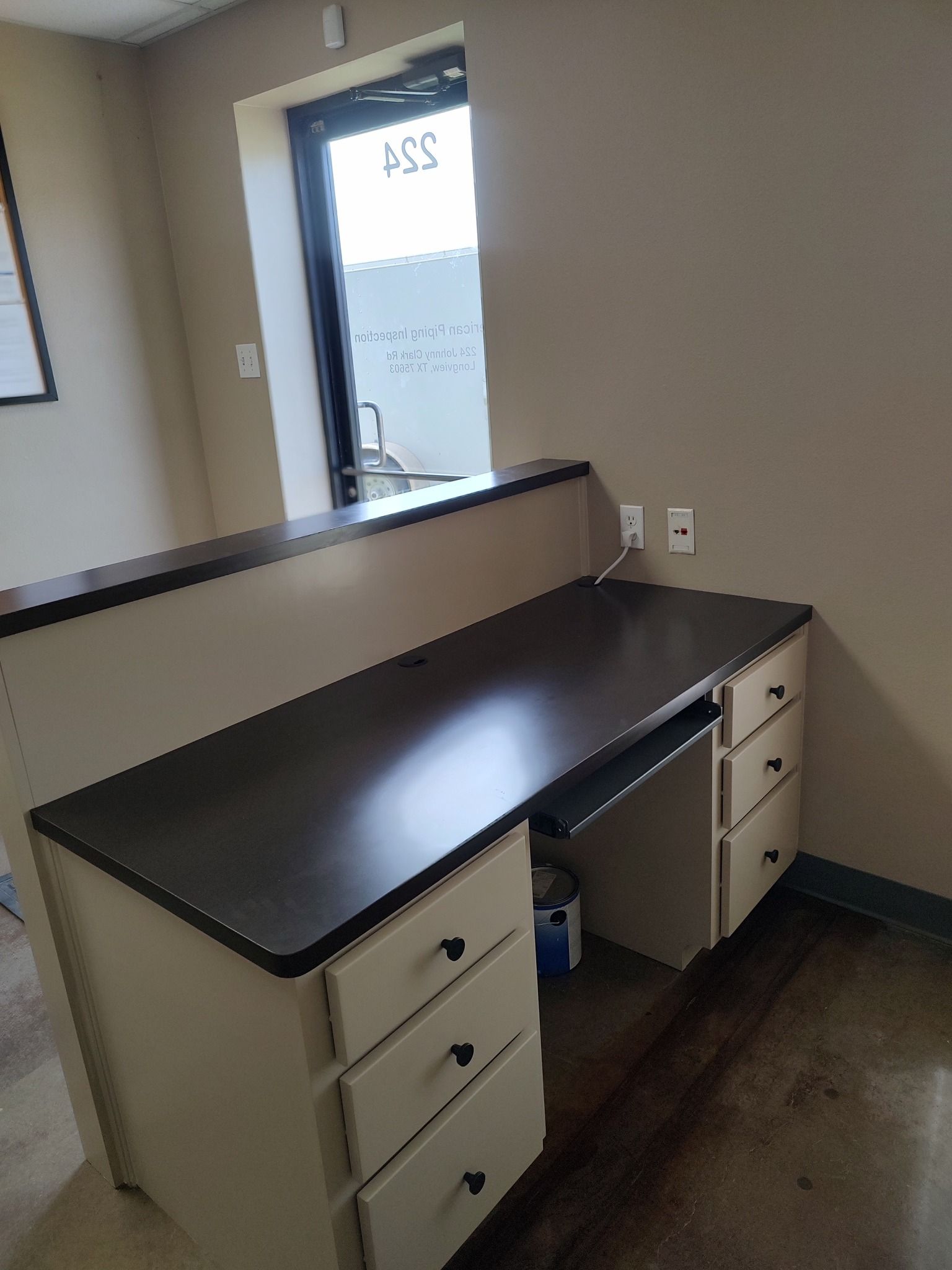 A desk with drawers and a window in a room.