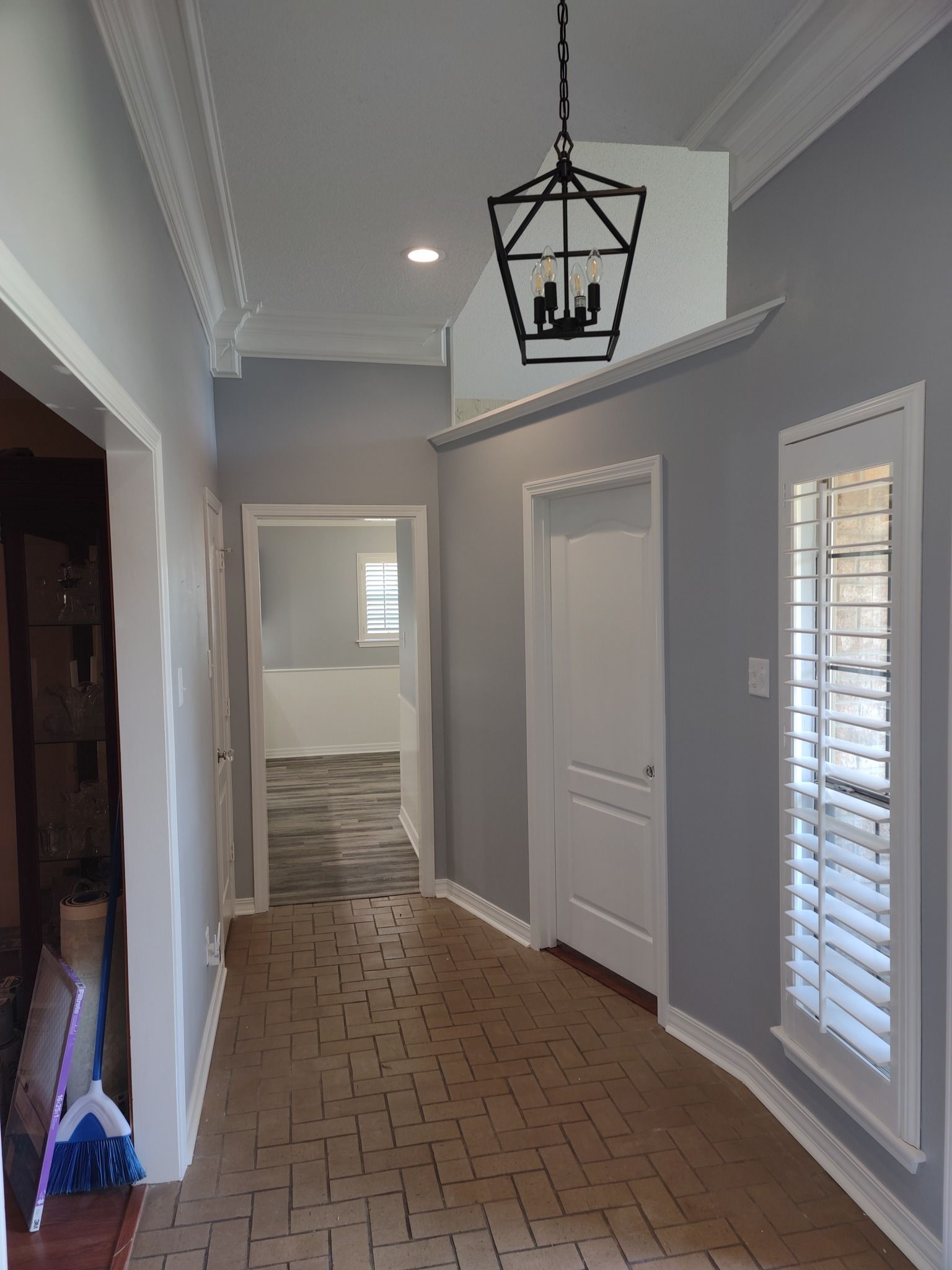 A hallway with a lantern hanging from the ceiling and shutters on the windows.