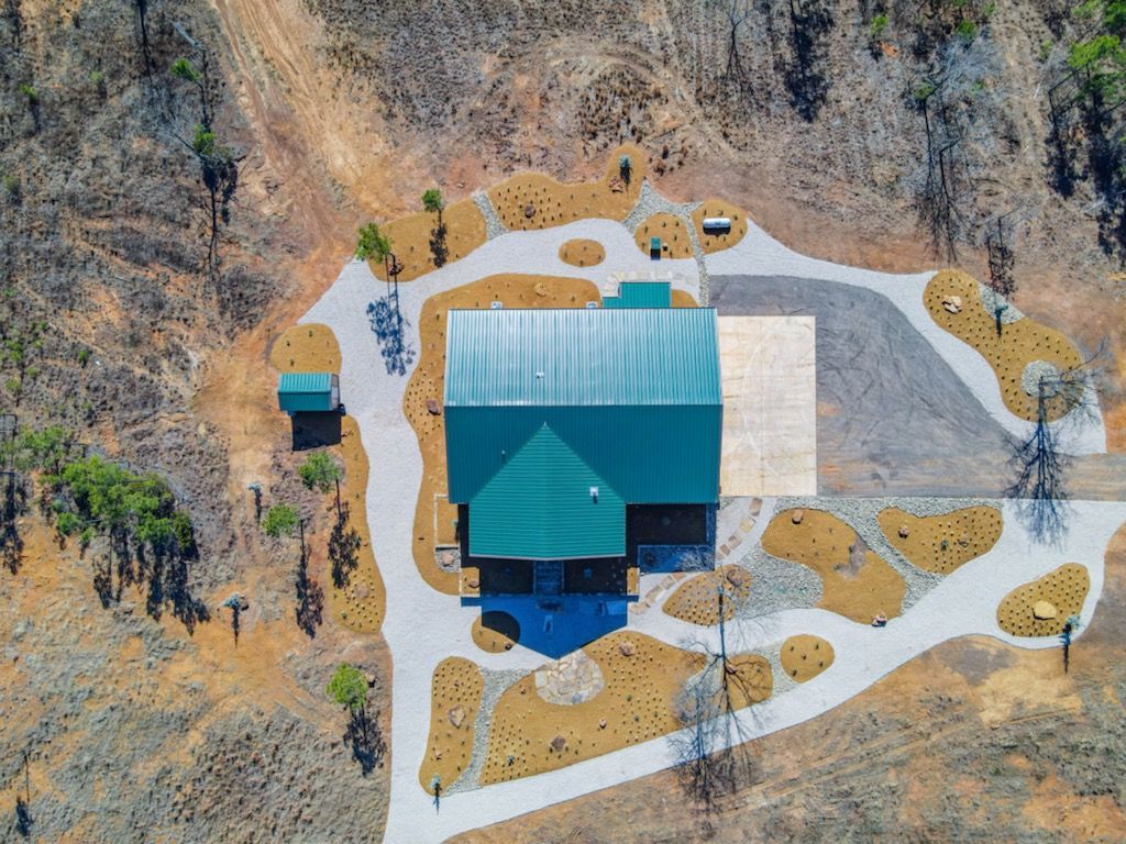 An aerial view of a house in the middle of a forest.