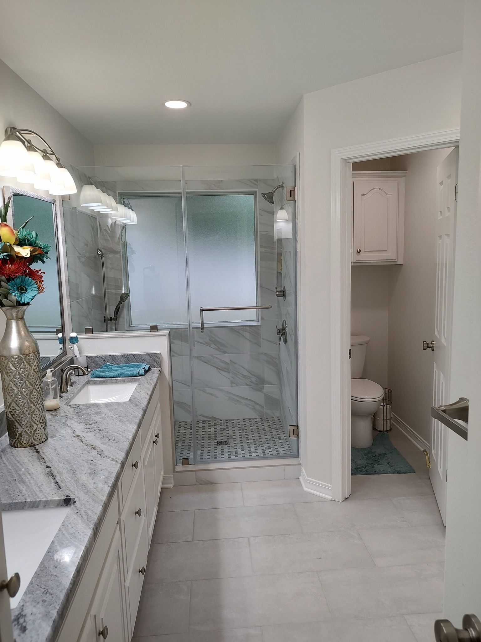 A bathroom with a walk in shower , sink , toilet and mirror.