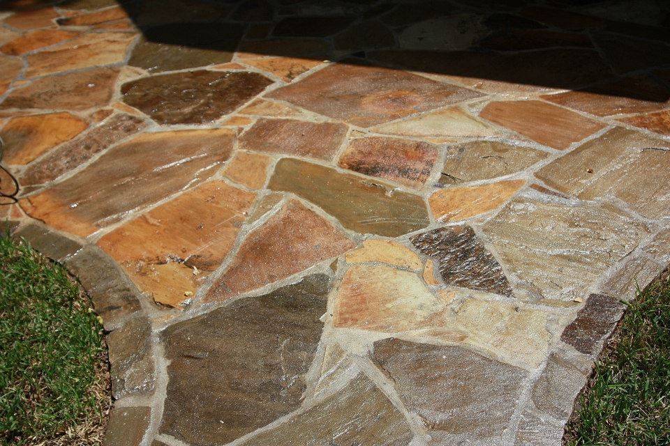 A stone walkway with a black doormat in the background