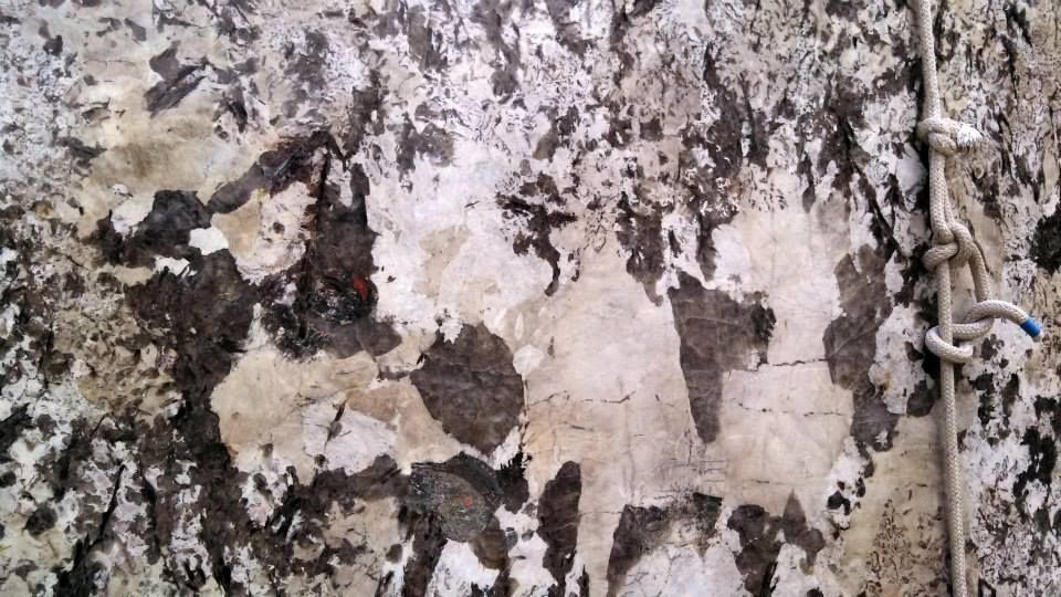 A close up of a dirty wall with a rope hanging from it.