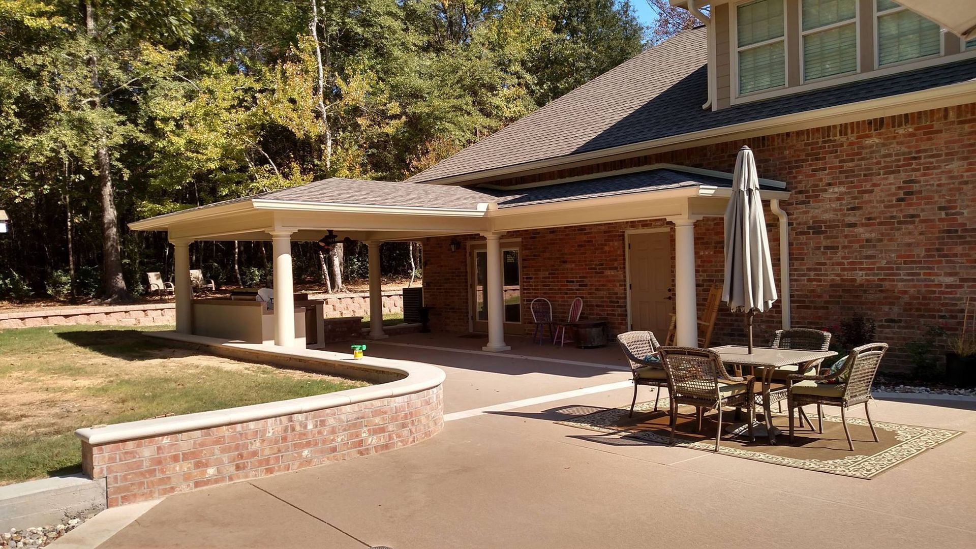 A brick house with a patio area with a table and chairs and an umbrella.