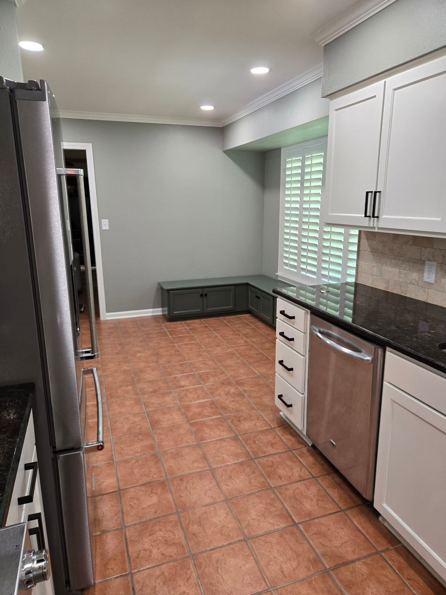 A kitchen with stainless steel appliances and white cabinets.