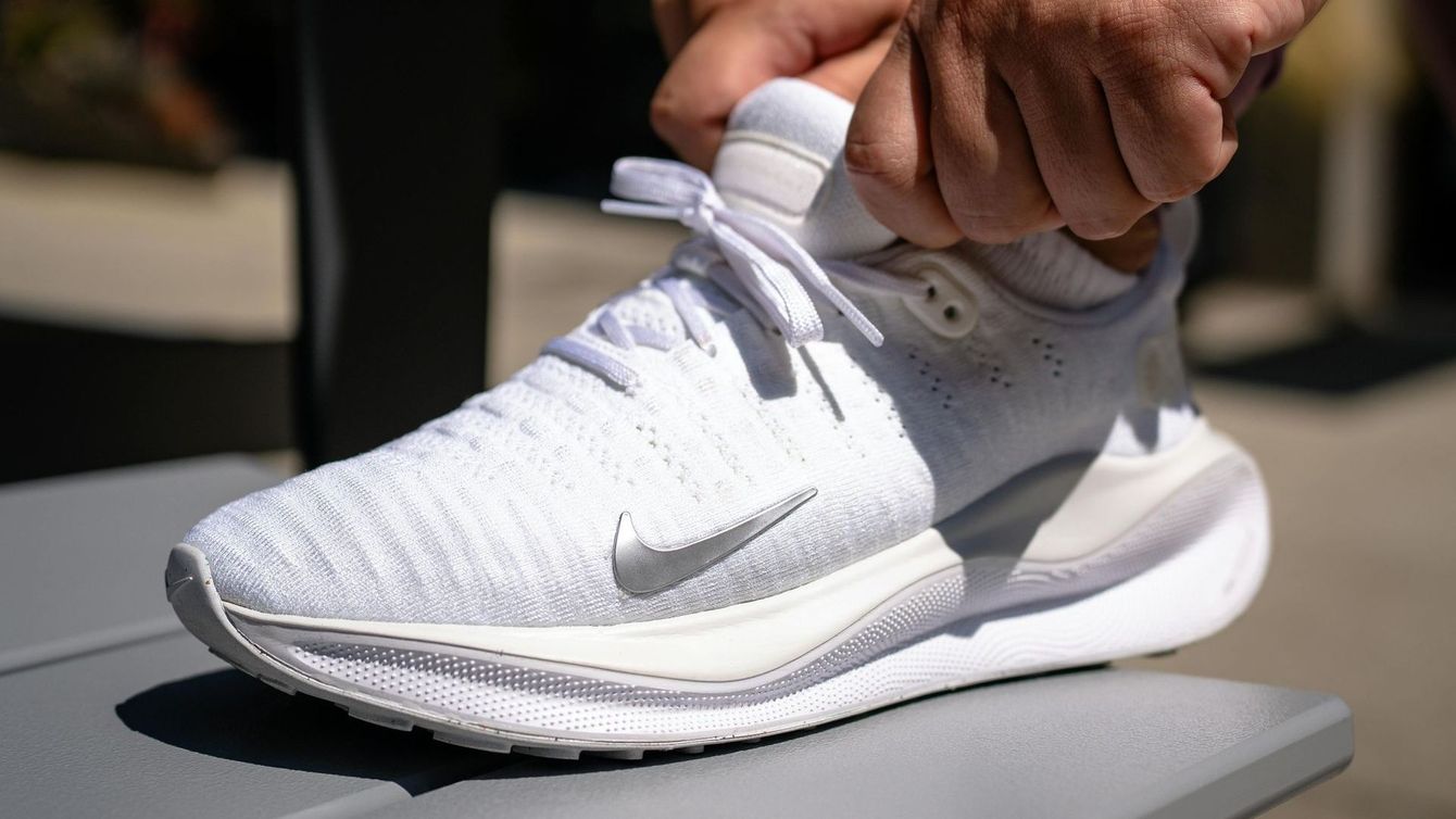 A person is tying their white nike shoes on a bench.