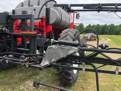 A red and black tractor is parked in a grassy field.