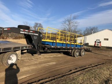 A trailer is being towed down a dirt road by a truck.