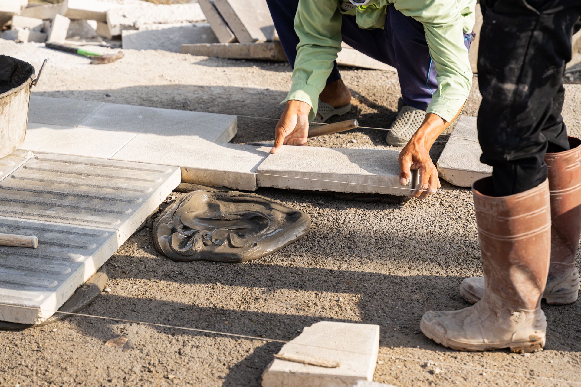 Workers leveling slabs on a home foundation surface.