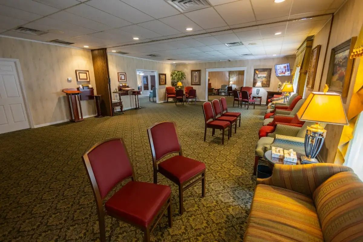 Interior of a funeral home waiting area: chairs, couches, and framed art.