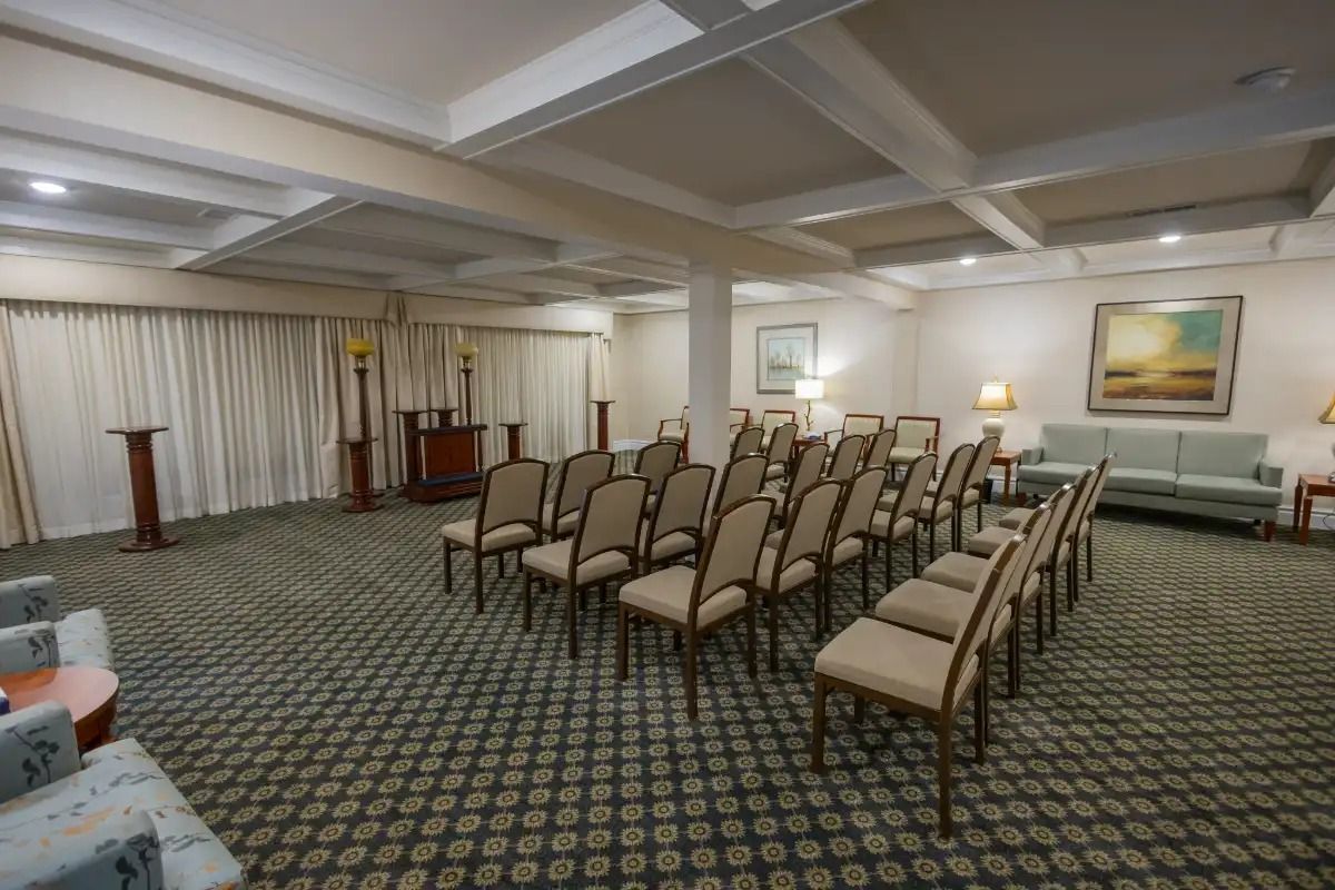 Funeral home chapel with chairs facing an altar, green carpet, and cream-colored walls.