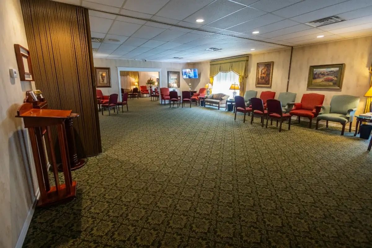 Waiting room with armchairs, green carpet, and paintings on the wall.