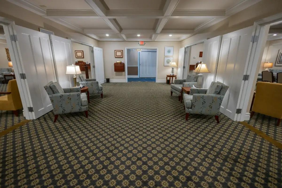 Lobby with seating areas, patterned carpet, white dividers, and artwork on the walls.