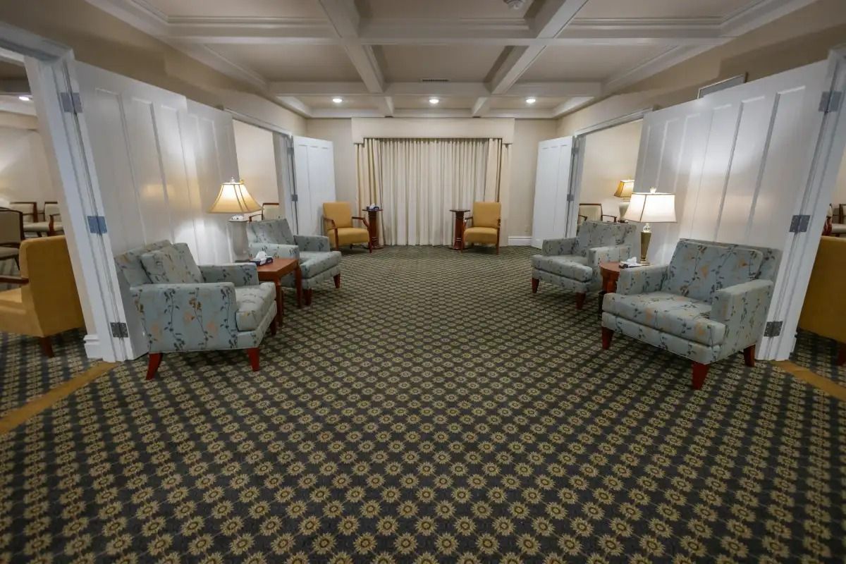 Awaiting area with patterned carpet, armchairs, lamps, and sheer dividers.