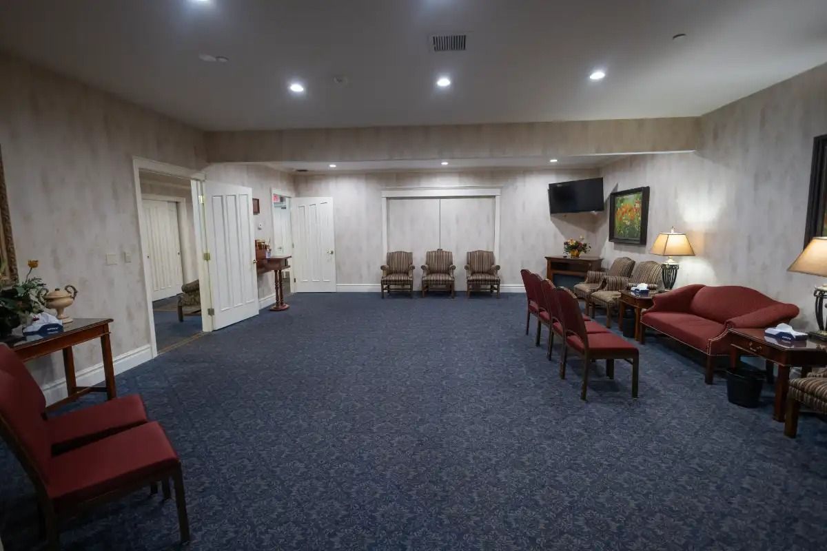 Interior of a funeral home: carpeted room with chairs and sofas.