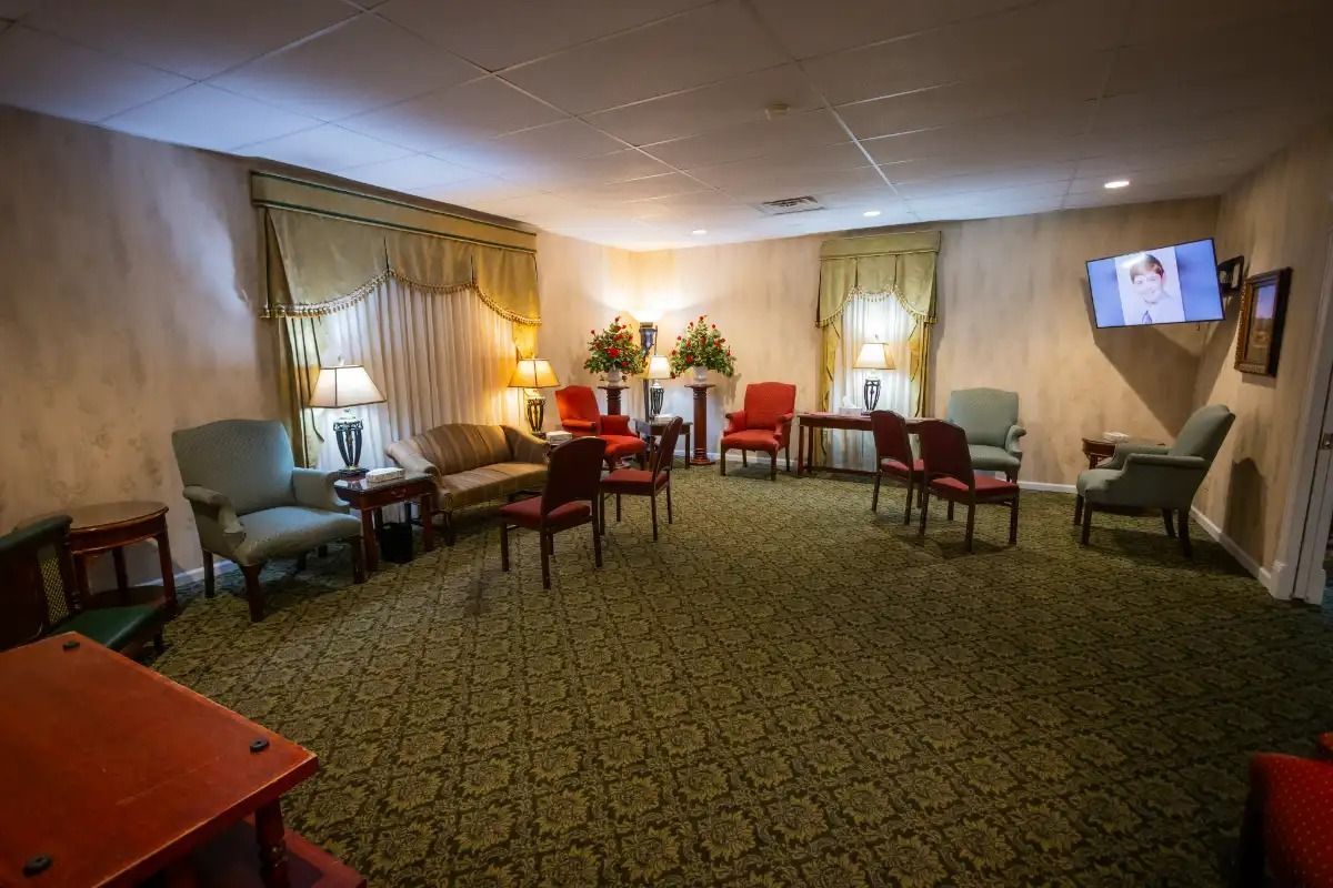 Waiting room with chairs, a sofa, floral arrangements, and a TV.