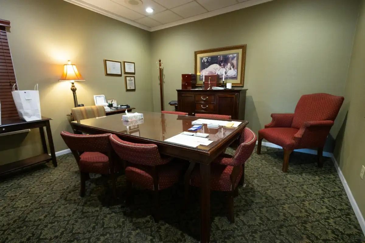 Conference room with table, red chairs, mahogany cabinet, and horse painting.