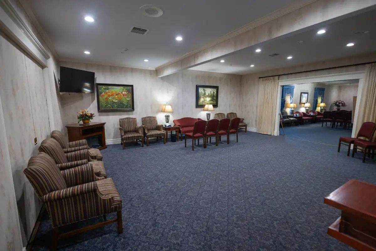 Interior of a funeral home waiting area with seating, art, and dark blue carpet.