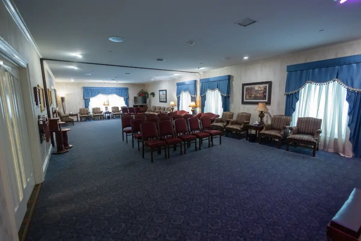 Funeral home chapel with blue carpet, red chairs, and blue curtains.