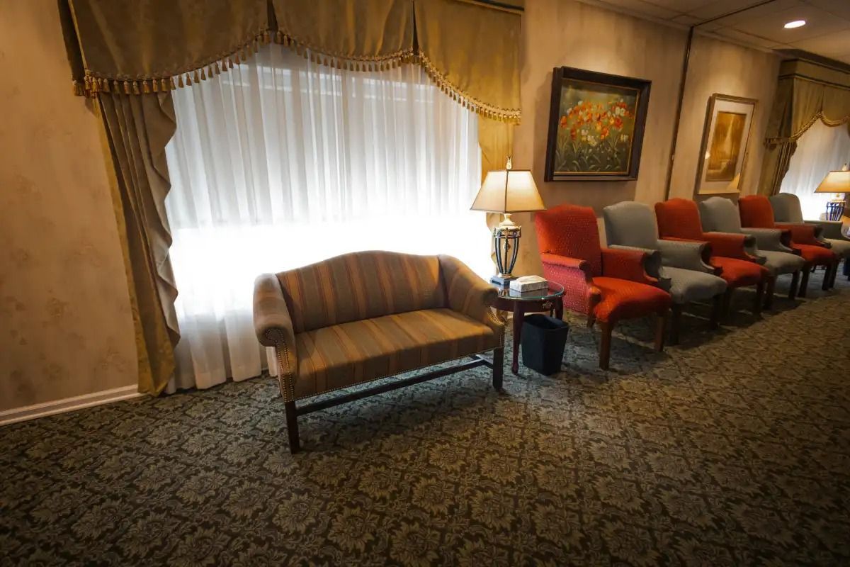 Waiting room with couch, chairs, window, artwork, and a lamp.