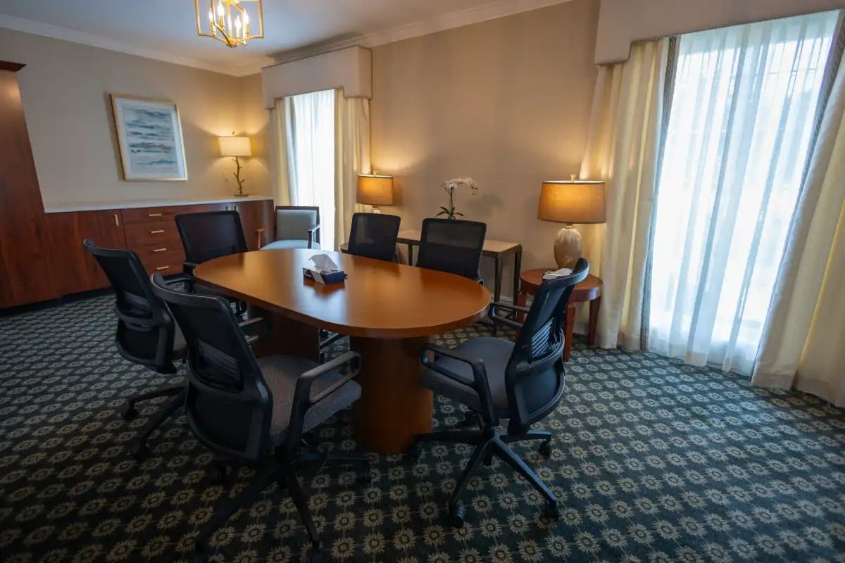Conference room with oval table, black chairs, lamps, and patterned carpet.