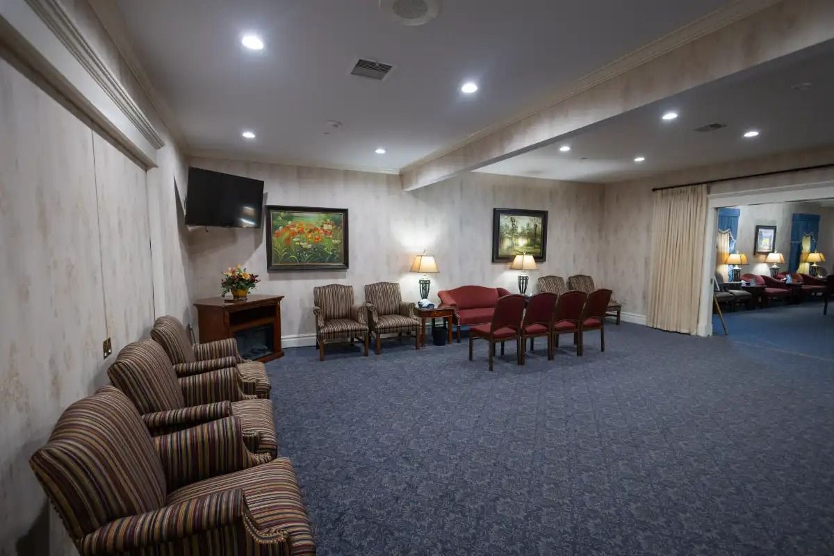 Interior of a waiting room with chairs, artwork, and an open doorway leading to another room.