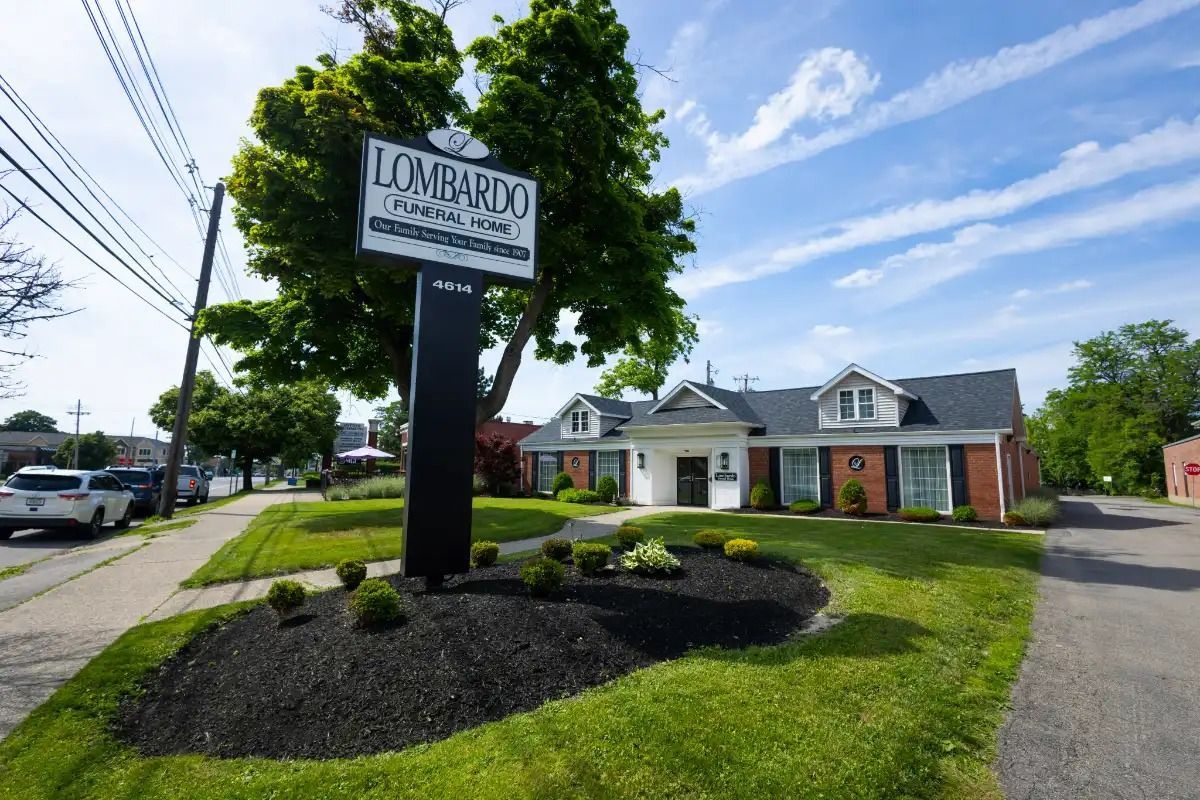 Lombardo Funeral Home building with sign; green lawn, black mulch, blue sky.