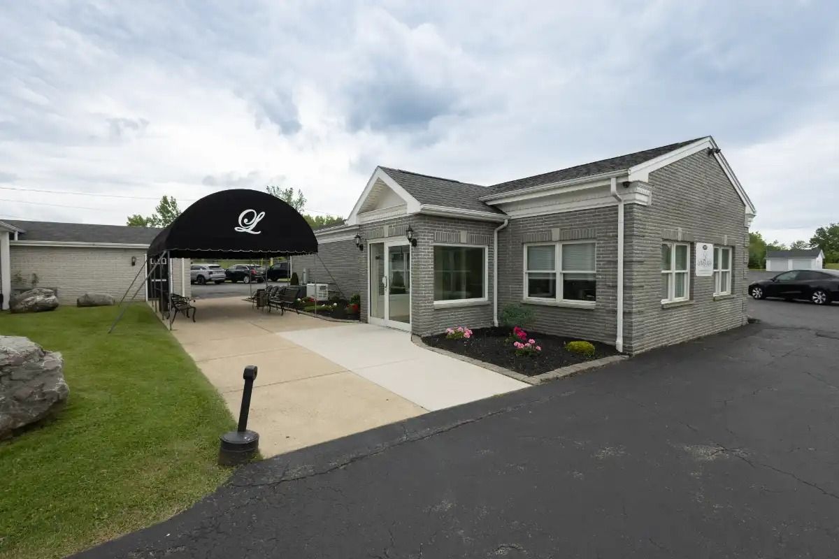 Office building with gray siding, black awning, and paved driveway.