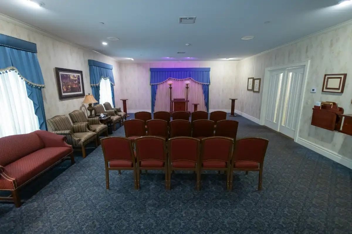 Funeral home chapel with red chairs, blue curtains, and a stage area.