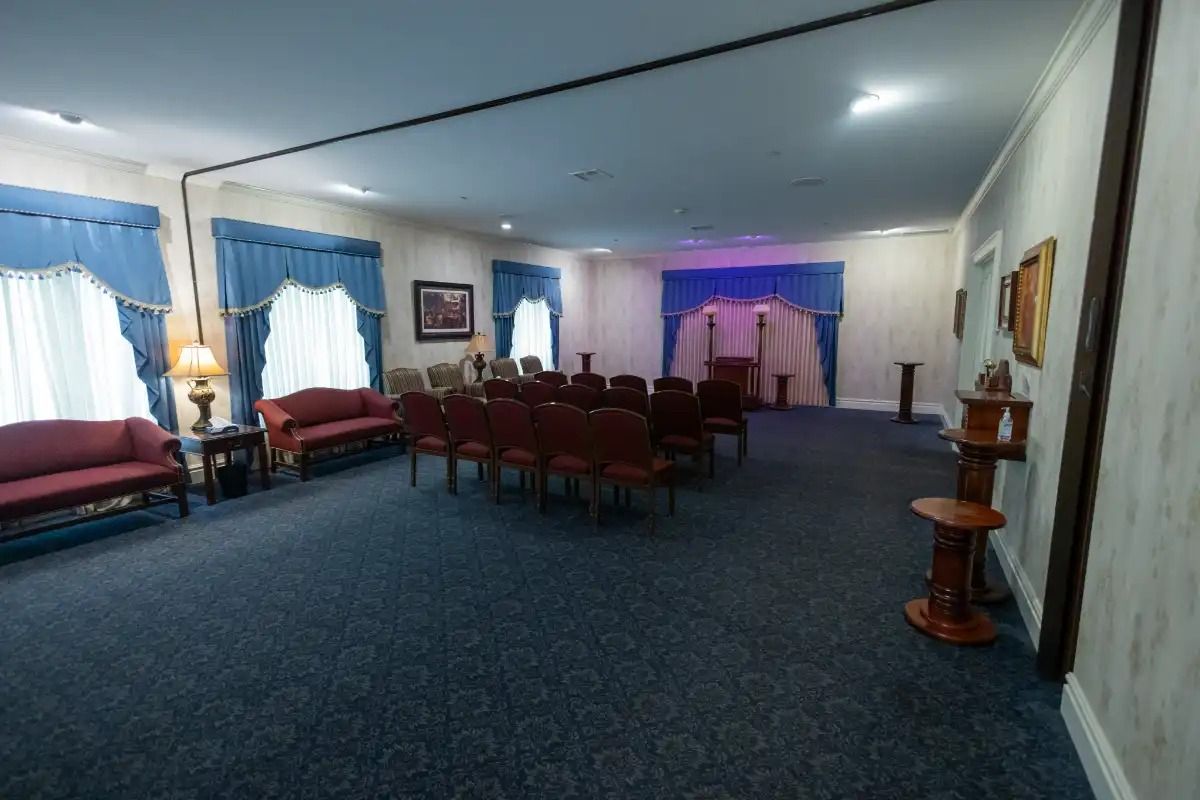 Funeral home interior with seating, dark blue carpet, and a light-up stage.