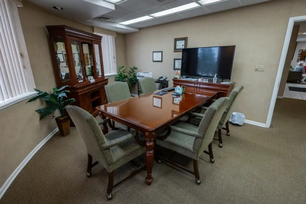 A conference room with a mahogany table, chairs, and a TV on a cabinet.
