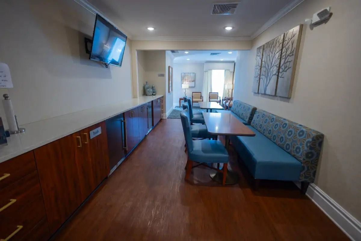 Interior shot of a dining/sitting area with a long built-in bench, table, chairs, and cabinets along a wall.