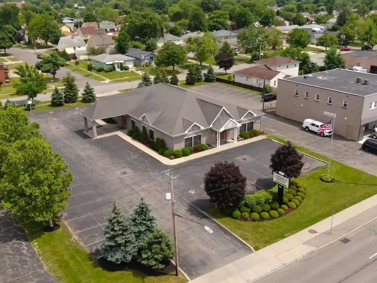 Aerial view of a brick building with a long, angled roof and ample parking in a residential area.