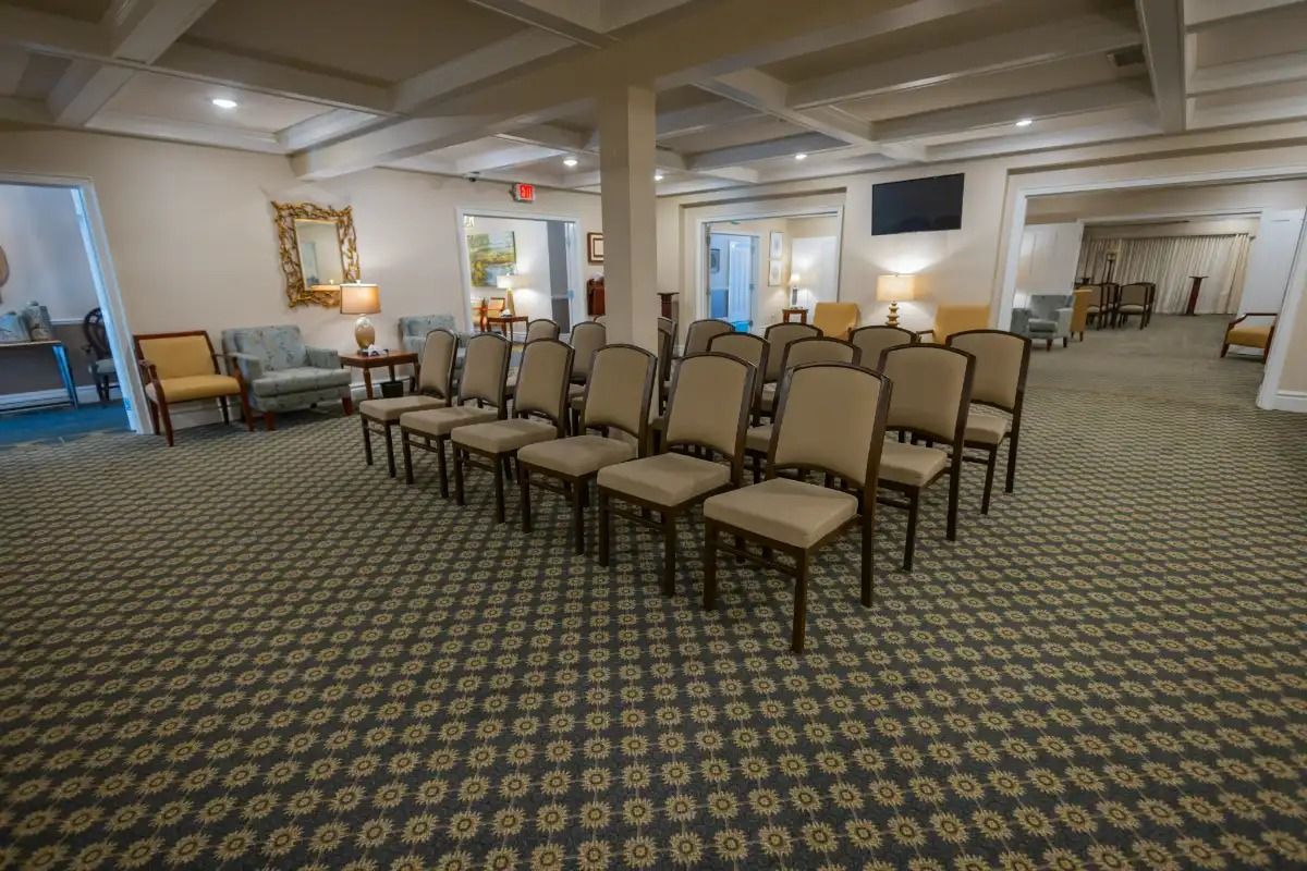 A funeral home viewing room, with rows of chairs facing an open area.