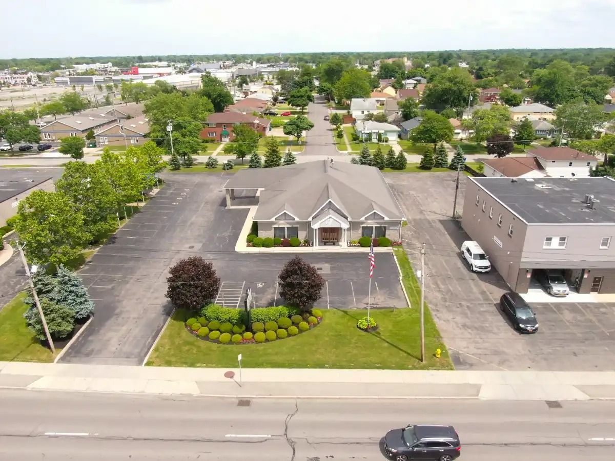 Aerial view of a business with landscaping and parking, residential neighborhood in the background.